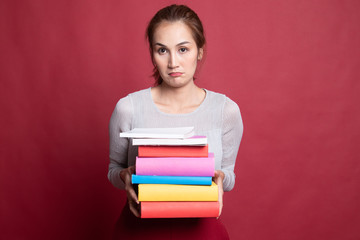 Unhappy young Asian woman studying  with may books.