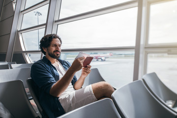 A man sits in a waiting room at the gate at the airport.