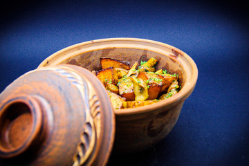 Roasted potatoes with mushrooms and pork on black background
