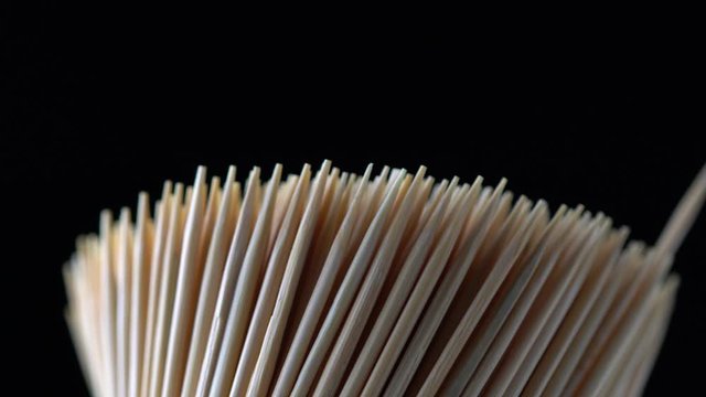 Extreme macro close up shot of man fingers pick up or taking toothpick out of rotating bunch 4K. Concept of personal teeth hygiene or oral tooth care after meal. Caries prevention. Dental healthcare.