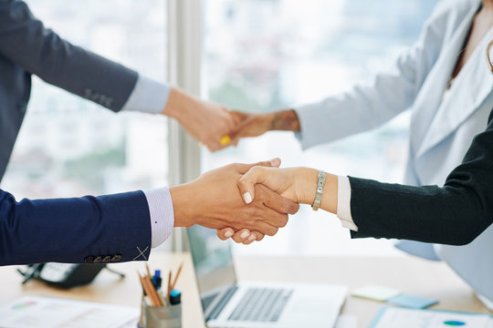 Hands of business executives shaking hands after successful business meeting in office