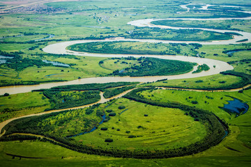 Fototapeta na wymiar View of the valley of a meandering river among green fields and forests. Aerial photography