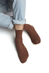 Cropped shot of a man's foots in blue jeans, lying on a white background. It is brown socks on his foots. 
