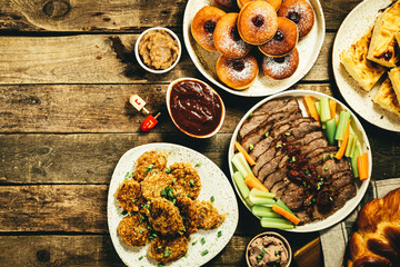 Selection of traditional hanukkah food for festive dinner - Potato Latkes, Applesauce, Challah, Beef Brisket, Sufganiot, Noodle Kugel, Julienned Vegetables
