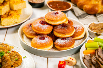 Selection of traditional hanukkah food for festive dinner - Potato Latkes, Applesauce, Challah, Beef Brisket, Sufganiot, Noodle Kugel, Julienned Vegetables