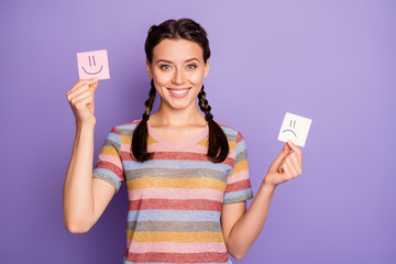 Photo of funny lady holding paper emoticons good and bad mood recommending positive emotions wear...
