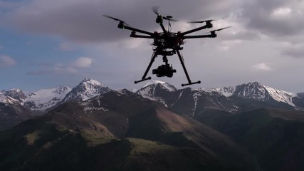 Rise Copter in the Air. Radio controlled hexacopter rises into the air from the ground position on the background of snowy mountains