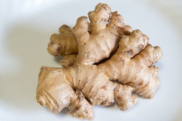 Ginger root on plate. Fresh organic ginger root on white plate. No people, isolated. Fresh healthy spice, natural medicine.