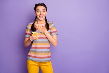 Portrait of excited funny youth girl use social network on her smartphone read wonderful blogs get notification scream wow omg wear yellow modern outfit isolated violet color background