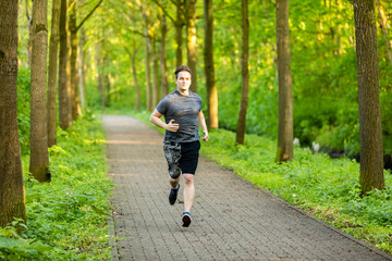 young man runs in a forest and makes fitness