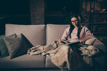 Photo of homey lady can't sleep until read love novel to end interested book worm addiction sitting couch covered warm blanket casual clothes spectacles dark living room indoors