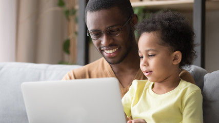 Close up of smiling black dad and son using laptop