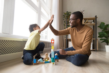 Excited black dad and son give high five playing together