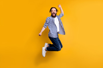 Fototapeta na wymiar Full length body size view of nice attractive cheerful cheery bearded guy in checked shirt jumping rejoicing having fun isolated over bright vivid shine vibrant yellow color background