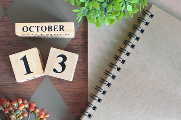 October 13. Date of October month. Number Cube with a flower and notebook on Diamond wood table for the background.