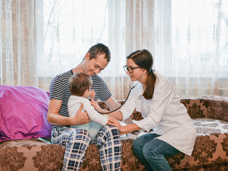 Childrens doctor listens to a child with a phonendoscope. the doctor is at home. call the address. Doctor on call. Phonendoscope, stethoscope. The doctor listens to the breath of a child with a phonen