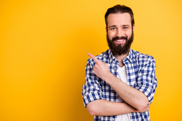 Close-up portrait of his he nice attractive cheerful cheery confident bearded guy in checked shirt showing copy space ad advert isolated over bright vivid shine vibrant yellow color background