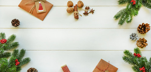 Fototapeta na wymiar Christmas frame made of fir branches, red berries, spices, nuts and gifts on rustic wooden table. Christmas holiday background. Flat lay, top view, copy space.