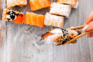 Sushi and soy sauce in a bowl and wooden chopsticks on a gray wooden table. Japanese food. Sushi Set. Variety of rolls. Menu.