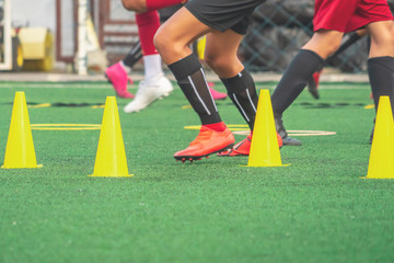 Children feet running and practicing on soccer field with cone and marker for football academy...