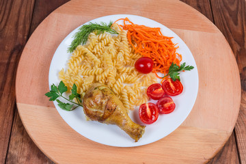 Grilled chicken leg with cooked spiral pasta, tomatoes, carrot salad