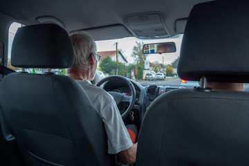 senior man driving car, wide angle interior view