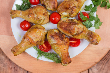 Grilled chicken legs with tomatoes and greens, fragment, top view