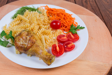Grilled chicken leg with cooked spiral pasta, tomatoes, carrot salad