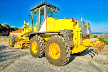 Yellow bulldozer on wheels laying asphalt concrete. Building work on a road. Work in progress, industrial machine.