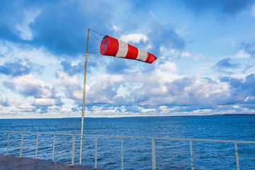 Windmill cone on a pier in a seaport in windy weather.
