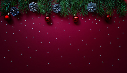 Christmas composition. Fresh fir tree branches, decorations on red background. Christmas, winter, new year concept. Flat lay, top view, copy space.