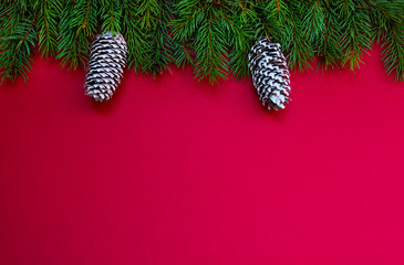 Christmas holidays composition on red background with copy space for your text. Christmas red decorations, fir tree branches on red background. Flat lay, top view, copy space.