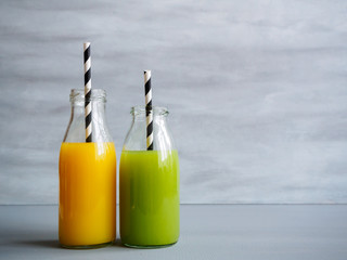 Oranger und grüner Fruchtsaft in einer Glasflasche mit Strohhalm, Diät, gesunde Ernährung