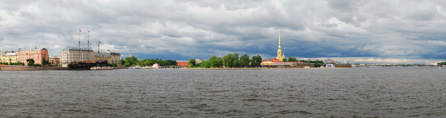 Panoramic view of the Peter and Paul Fortress in St. Petersburg on a cloudy day, against a background of lead clouds.