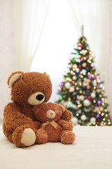 Merry Christmas! Children's toys teddy bears big and small are sitting on the sofa against the background of the Christmas tree.