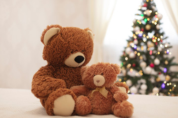 Merry Christmas! Children's toys teddy bears big and small are sitting on the sofa against the background of the Christmas tree.
