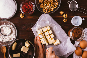 Woman's hands dices butter on wooden table