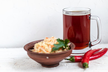 A large glass of cold beer. Fermented, pickled cabbage in a brown bowl.