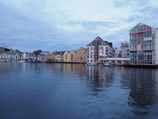 Yacht port and secessionist buildings reflected in water in european city of Alesund at Romsdal in Norway at evening
