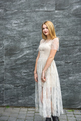Obraz premium Young woman in evening dress posing on city street, dark wall background
