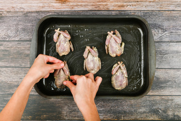 quail in hands. quail in human hands. cooking quail. lies on the brow, in front of the oven