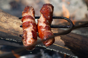 Grilling sausages with BBQ fork on open fire