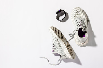 Sports watch and White Sneakers on a white background under the morning sun. The concept of running, fitness, cross fit. Morning running. Banner. Flat lay, top view
