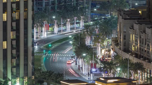 Intersection traffic night timelapse on Mohammed Bin Rashid Boulevard curves among the many illuminated skyscrapers and towers that comprise the Dubai city skyline.