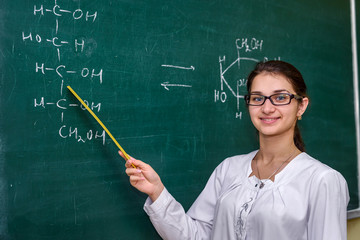 Female portrait. Chemistry teacher standing near class board pointing on it