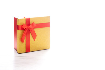 Bright golden and red present box with gift ribbon and bow