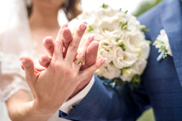 Wedding concept. Male and female hand with golden rings on flower bouquet