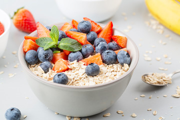 Healthy smoothie bowl with granola, fresh strawberries, blueberries, bananas, yogurt and mint. Healthy food, snack or breakfast. 