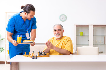 Young male doctor visiting old patient at home