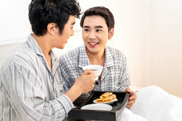 Asian homosexual couple in pajamas having a breakfast in the bed.Concept LGBT gay.